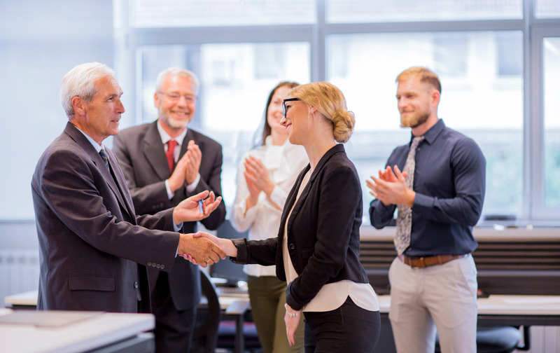 employees shaking hands after a faewell speech in the office