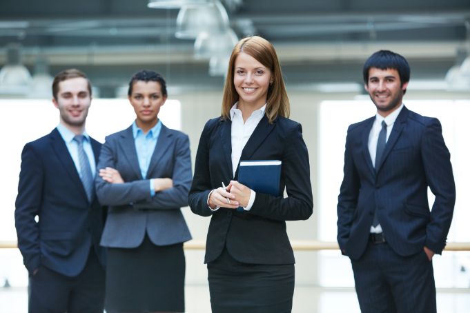 four business people standing together wearing business formals