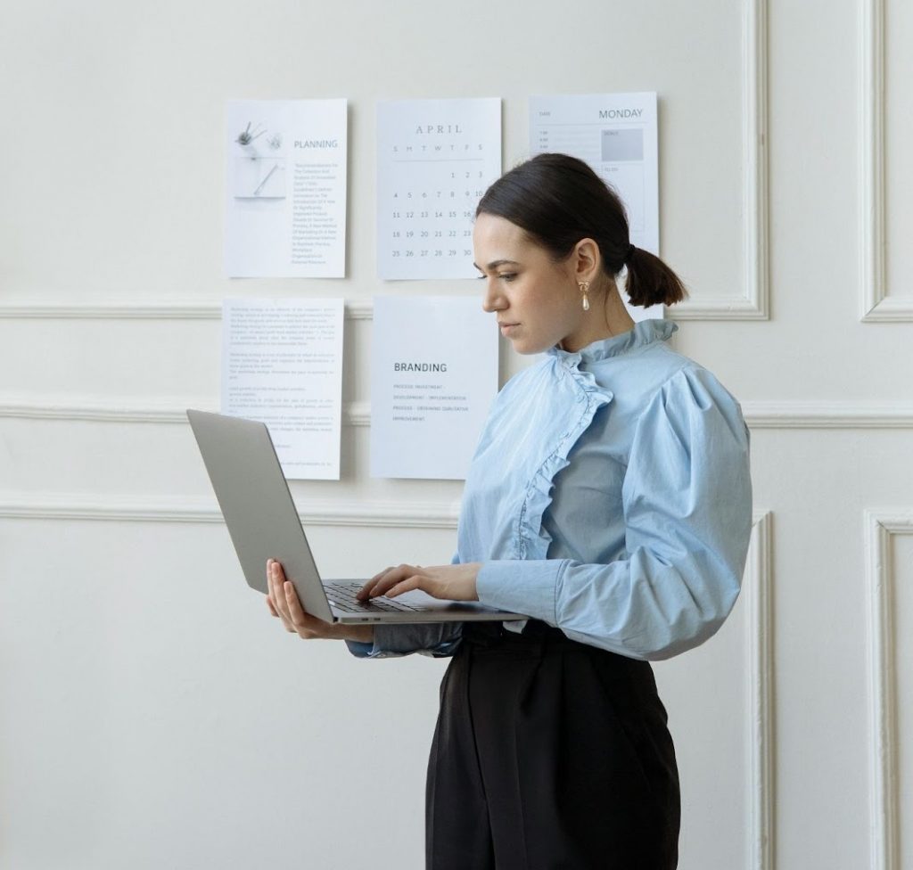 a female employee applying for a sabbatical leave while standing and typing on a laptop